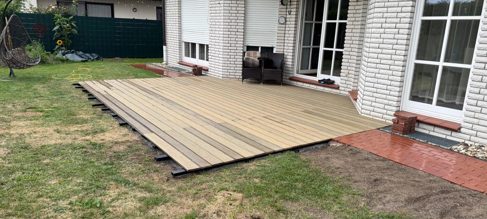 Neue Holzterrasse am Haus mit Anschluss an das Pflaster